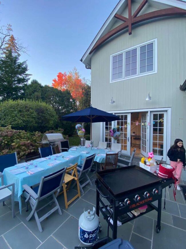 Backyard hibachi party setup with grill, table seating, and birthday decorations before guests arrive
