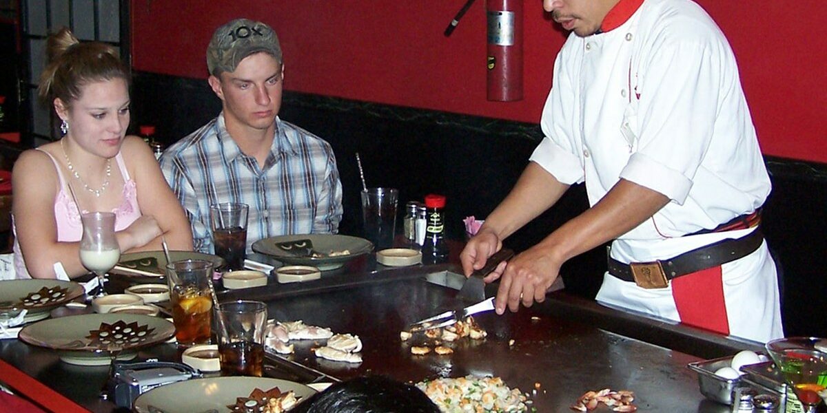 Hibachi dinner table at a teppanyaki restaurant with chef-grilled dishes served in front of guests Hibachi dinner table at a teppanyaki restaurant with chef-grilled dishes served in front of guests