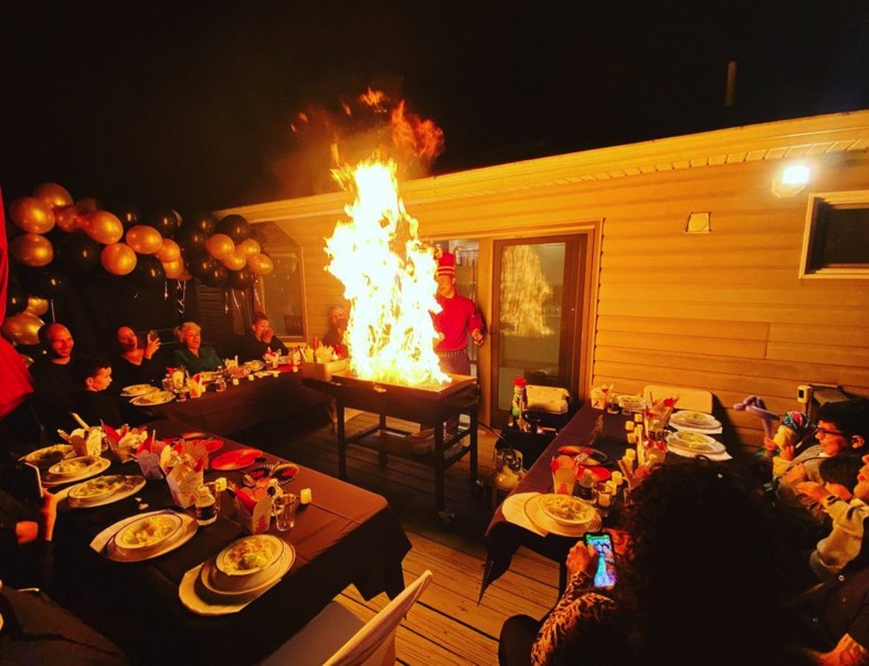Hibachi Royal chef flame show on an evening patio with guests seated at decorated party tables