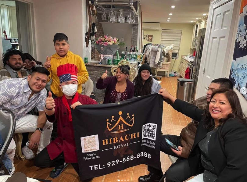 Hibachi Royal chef posing with a family group behind a Hibachi Royal banner at an indoor gathering